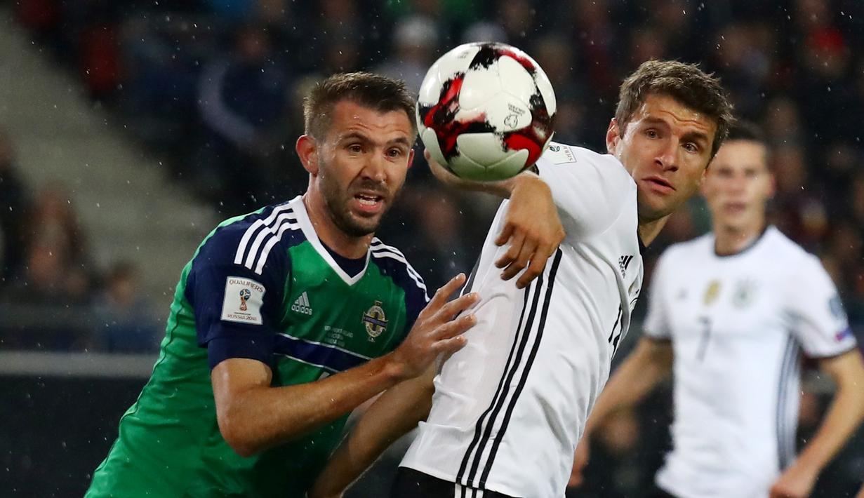 Striker Jerman, Thomas Muller (kanan), dijaga ketat pemain Irlandia Utara, Gareth McAuley, pada laga Grup C Kualifikasi Piala Dunia 2018 zona Eropa, di HDI-Arena, Hanover, Rabu (12/10/2016) dini hari WIB. (Reuters/Kai Pfaffenbach)