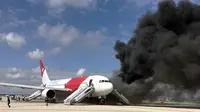 Kepulan asap keluar dari pesawat Boeing 767-200ER milik maskapai Dynamic International Airways yang terbakar saat akan lepas landas di Bandara Fort Lauderdale, Florida, Kamis (29/10). 15 orang terluka akibat kejadian tersebut. (AFP PHOTO/Andres Gallego)