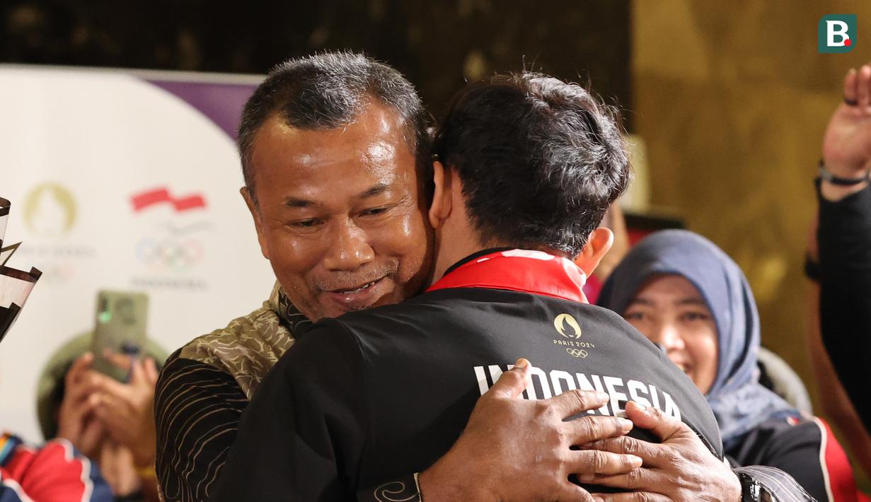 <p>Veddriq Leonardo disambut dengan pelukan hangat oleh sang bapak usai tiba di Bandara Internasional Soekarno-Hatta, Tangerang, Selasa (13/8/2024). (Abdul Aziz/Bola.com).</p>