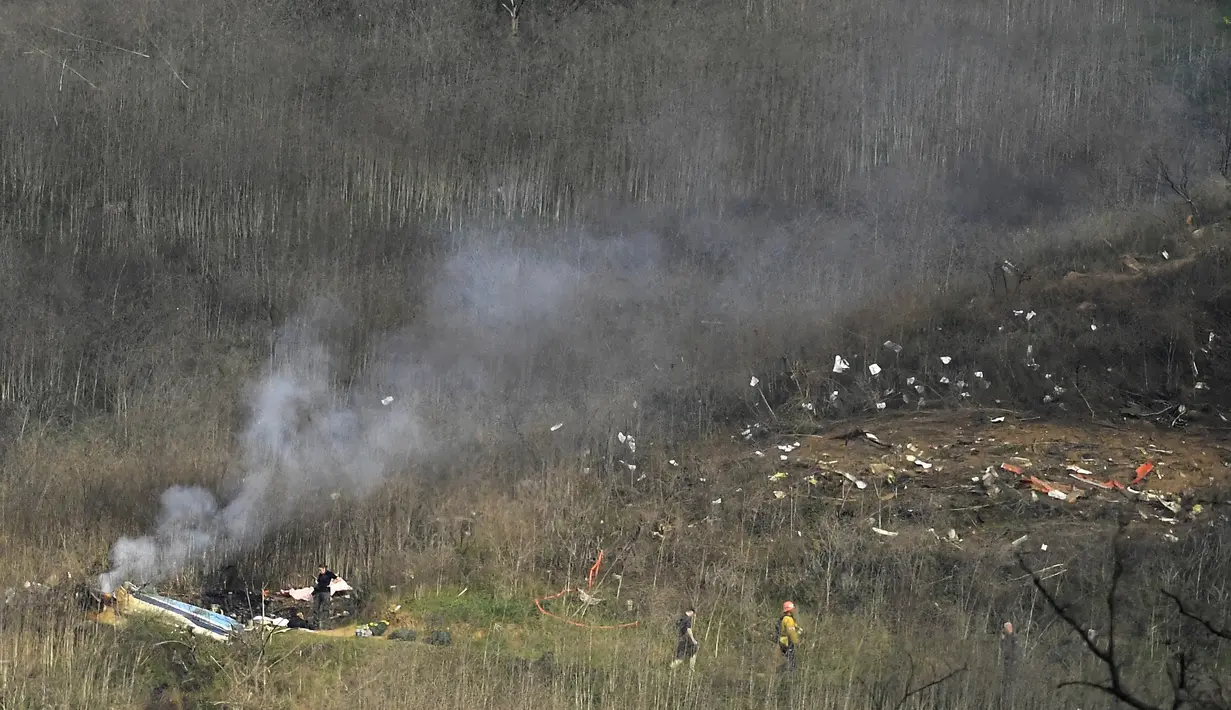 Sejumlah petugas berusaha mengevakuasi korban jatuhnya helikopter di Calabasas, California, Minggu (26/1/2020). Legenda NBA, Kobe Bryant, menjadi salah satu korban tewas pada kecelekaan helikopter berjenis Sikorsky S-76B itu. (AP/Mark J. Terrill)
