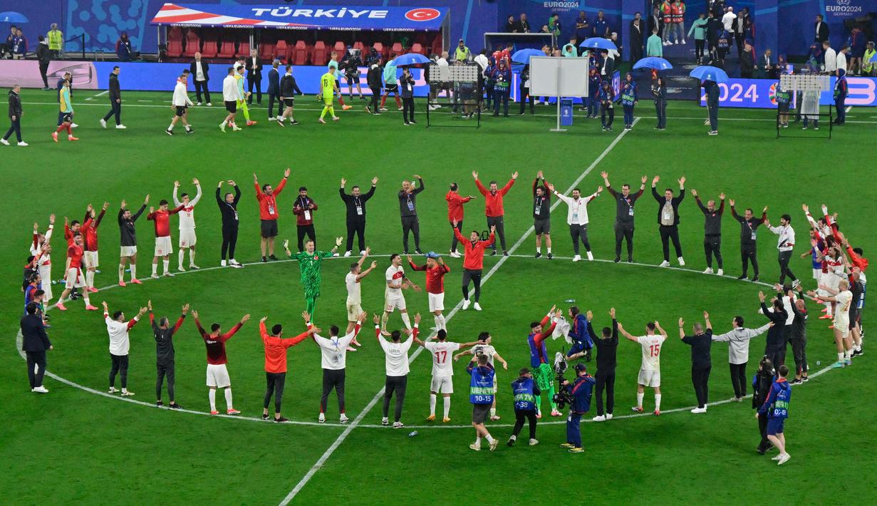 Para pemain dan anggota tim Turki merayakan kemenangan laga babak 16 besar Euro 2024 melawan Austria di Red Bull Arena, Leipzig, pada 2 Juli 2024 atau Rabu 3 Juli 2024 dini hari. (JOHN MACDOUGALL/AFP)