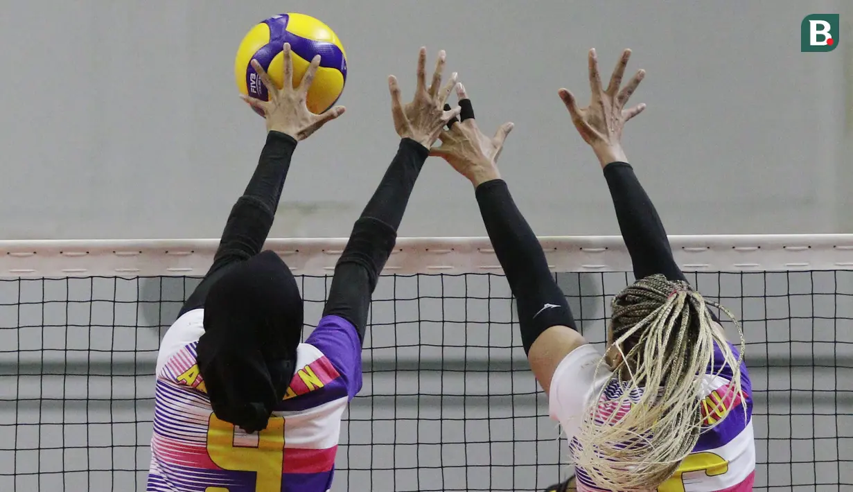 Pemain Jakarta Mandiri Popsipo Polwan, Arsela Nuari Purnama (kiri) berusaha memblok bola smes pemain Gresik Petrokimia Pupuk Indonesia pada laga PLN Mobile Proliga 2022 di Padepokan Voli Jenderal Polisi Kunarto, Sentul, Jumat (28/1/ 2022). (Bola.com/M Iqbal Ichsan)