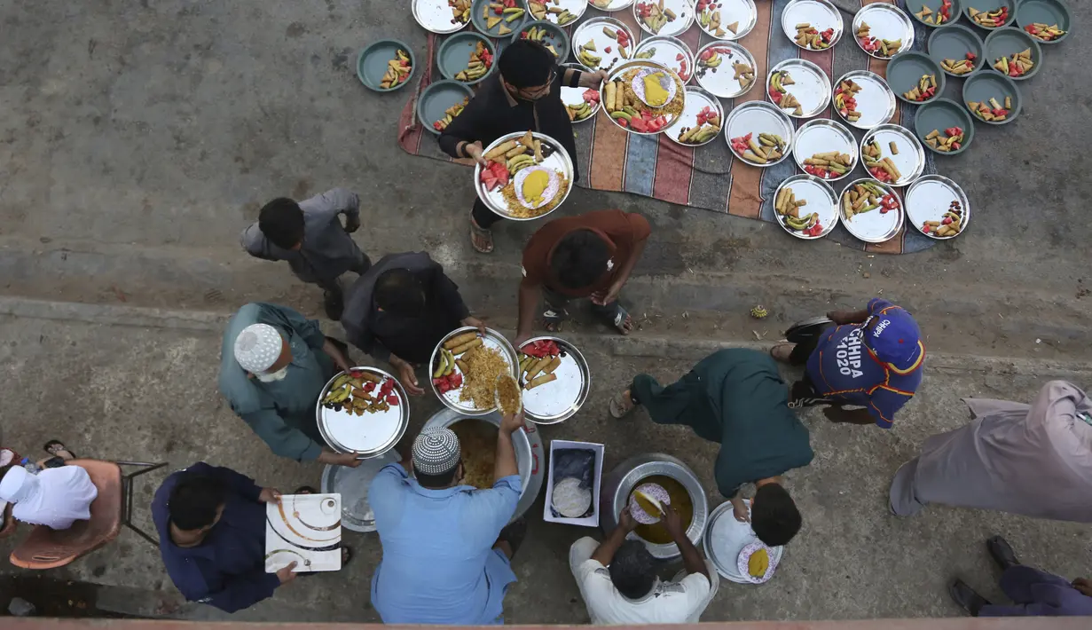 Relawan mengatur makanan untuk warga saat berbuka puasa bersama selama bulan suci Ramadan di Karachi, Pakistan, Selasa (12/5/2020). Warga berbuka puasa bersama setelah pemerintah melonggarkan lockdown terkait pandemi virus corona COVID-19. (AP Photo/Fareed Khan)