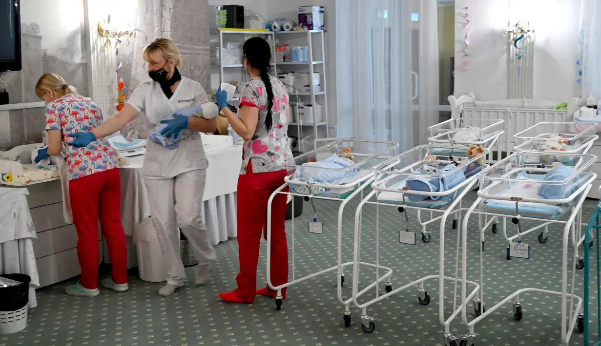 Perawat merawat bayi yang baru lahir dari skema ibu pengganti (surrogate mother) di Hotel Venice, Kiev, Ukraina, 15 Mei 2020. Komisioner Hak Asasi Manusia di Ukraina memperingatkan bahwa lockdown berkepanjangan dapat membuat banyak bayi menunggu terlalu lama. (Sergei SUPINSKY/AFP)