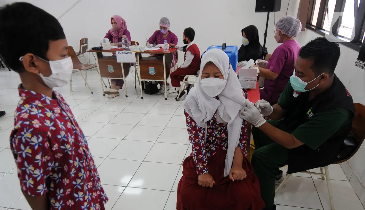 Petugas kesehatan menyuntikkan vaksin COVID-19 kepada siswa di SDN 02 Ciater, Tangerang Selatan, Selasa (14/12/2021). Mulai Hari ini, 11 provinsi di Indonesia secara serentak melaksanakan vaksinasi COVID-19 dengan sasaran anak berusia 6 hingga 11 tahun. (merdeka.com/Arie Basuki)
