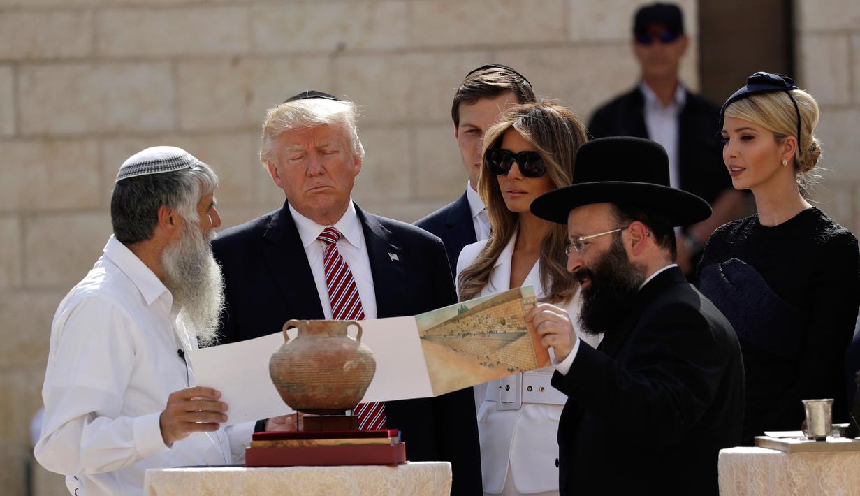 Presiden AS Donald Trump didampingi Ibu Negara, Melania dan Ivanka Trump serta sang suami, Jared Kushner, mendengarkan penjelasan Rabi atau guru Yahudi, Shmuel Rabinowitz saat mengunjungi Tembok Ratapan di Yerusalem, Senin (22/5). (AP Photo/Evan Vucci)
