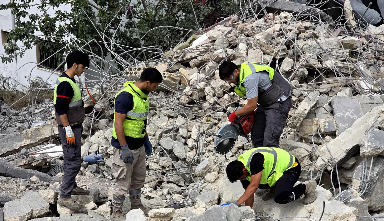 Para pekerja pertahanan sipil Lebanon menyisir reruntuhan, sehari setelah serangan Israel di desa Deir Qanun al-Nahr, Lebanon Selatan, pada Rabu 20 Mei 2026. (KAWNAT HAJU/AFP)