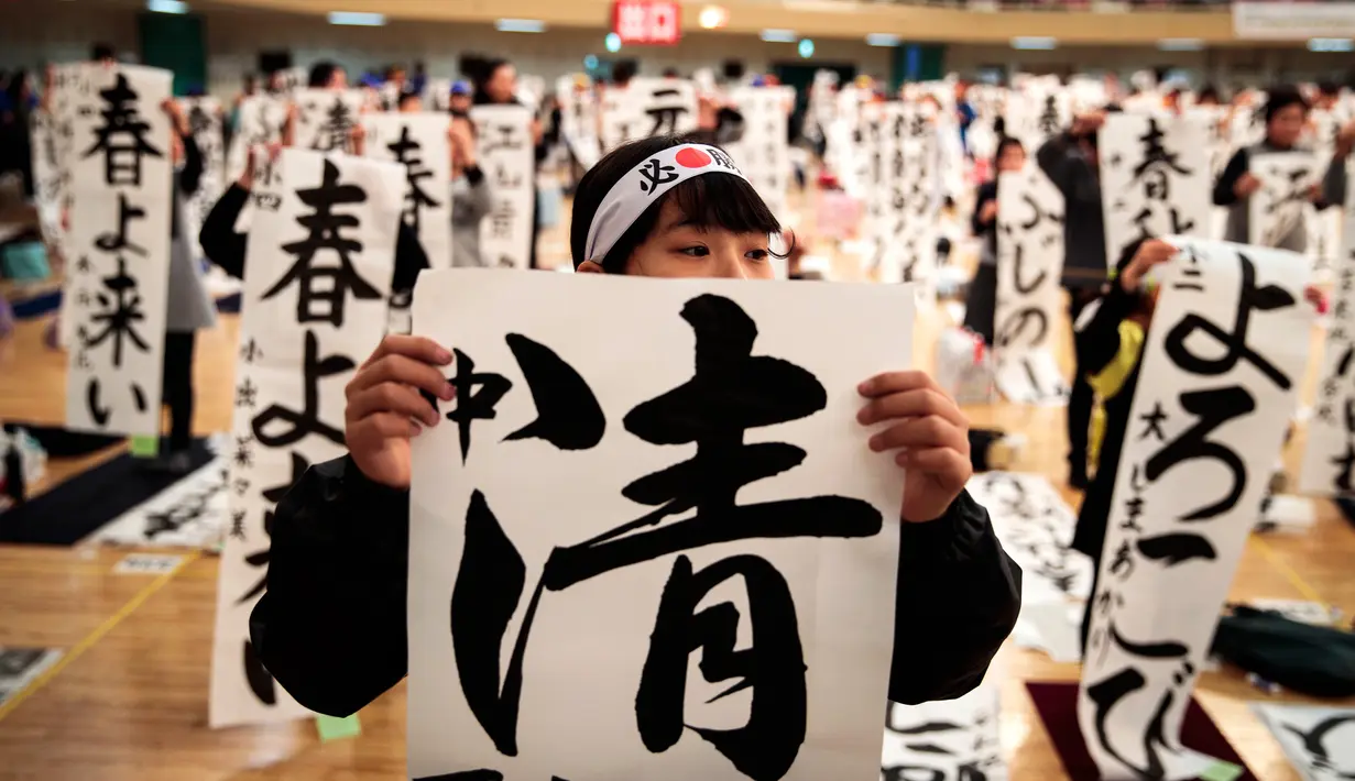 Peserta menampilkan tulisan Jepang mereka selama kontes kaligrafi  tahun baru di Tokyo, Sabtu (5/1). Sudah menjadi tradisi di Jepang jika semangat tahun baru digoreskan di atas kanvas dengan tulisan kaligrafi. (Behrouz MEHRI / AFP)