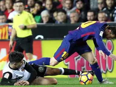 Pemain Barcelona, Lionel Messi berebut bola dengan pemain Valencia, Carlos Soler pada lanjutan La Liga Primera Division di Stadion Mestalla, Minggu (26/11). Valencia memaksa Barcelona meraih hasil imbang 1-1.  (AP/Alberto Saiz)