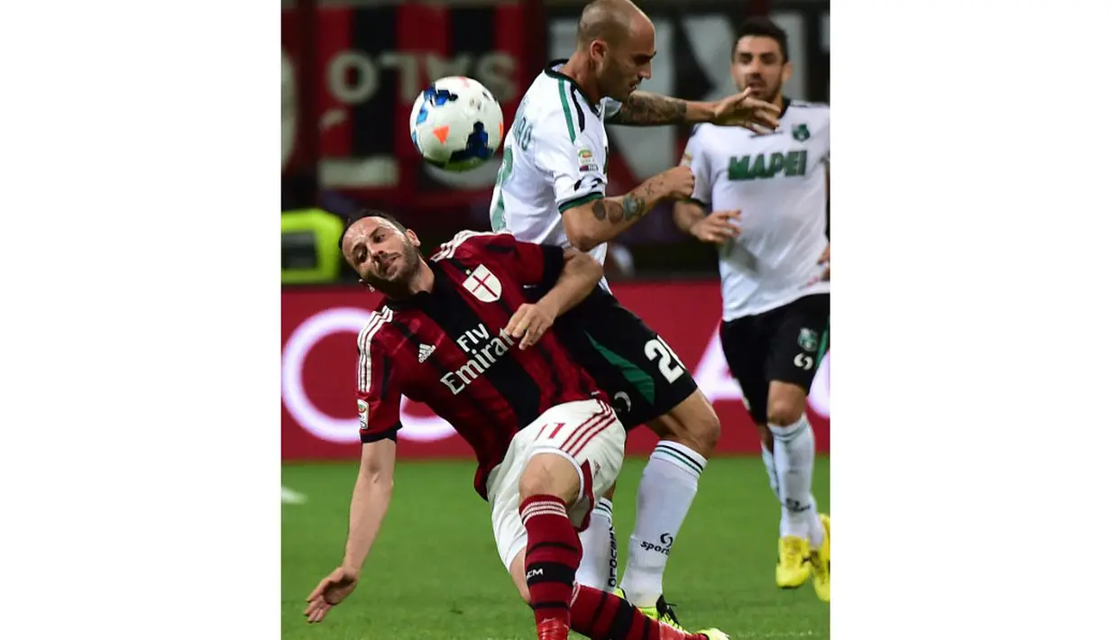 Penyerang AC Milan, Giampaolo Pazzini (kiri) terjatuh saat berebut bola dengan pemain belakang Sassuolo, Paolo Cannavaro, saat berlaga di Stadion San Siro, (18/5/2014). (AFP PHOTO/Giuseppe Cacace)