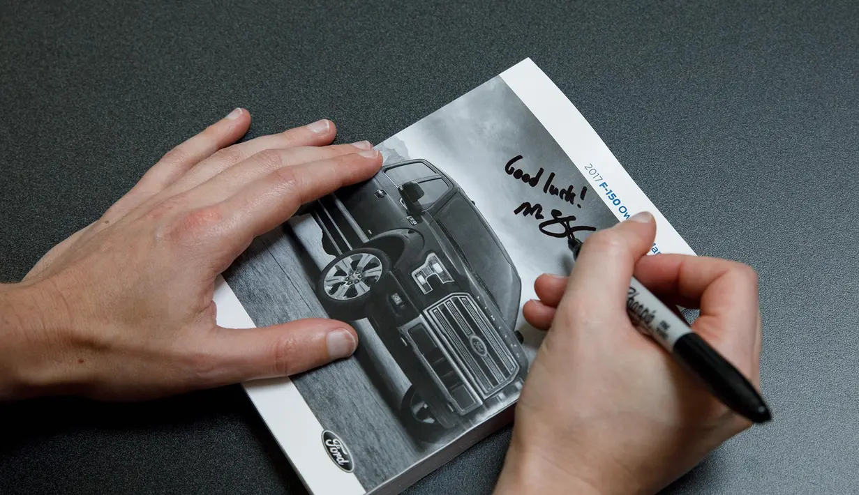 Mark Zuckerberg memberikan tanda tangan pada buku katalog dari perusahaan mobil Ford saat kunjungan ke pabrik mobil pikap legendaris Ford F-150 di Dearborn, Michigan, AS. (Facebook/Mark Zuckerberg)