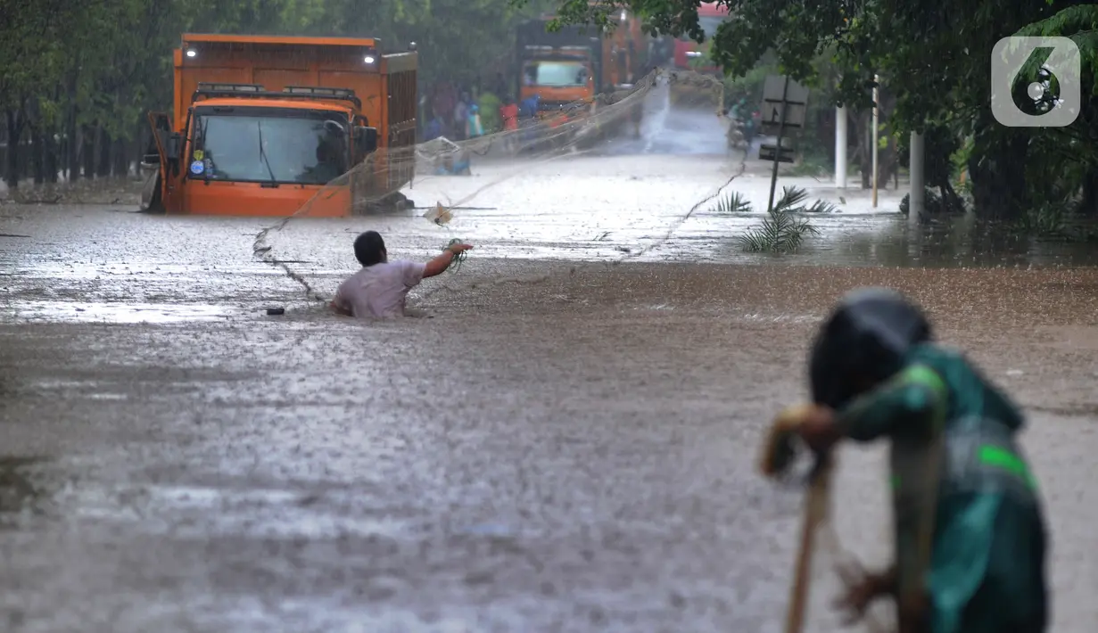 Warga menjala ikan di tengah jalan yang tertutup banjir di kawasan TB Simatupang, Jakarta Selatan, Sabtu (20/2/2021). Banjir terjadi akibat luapan Kali Serua yang berada di pinggir jalan tol. (merdeka.com/Arie Basuki)