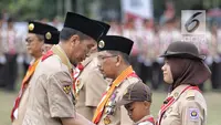 Presiden Joko Widodo memberi tanda kehormatan kepada seorang anak saat perayaan hari jadi Pramuka yang ke-57 di Lapangan Gajah Mada, Wiladatika, Cibubur, Jakarta, Selasa (14/8). (Liputan6.com/Faizal Fanani)