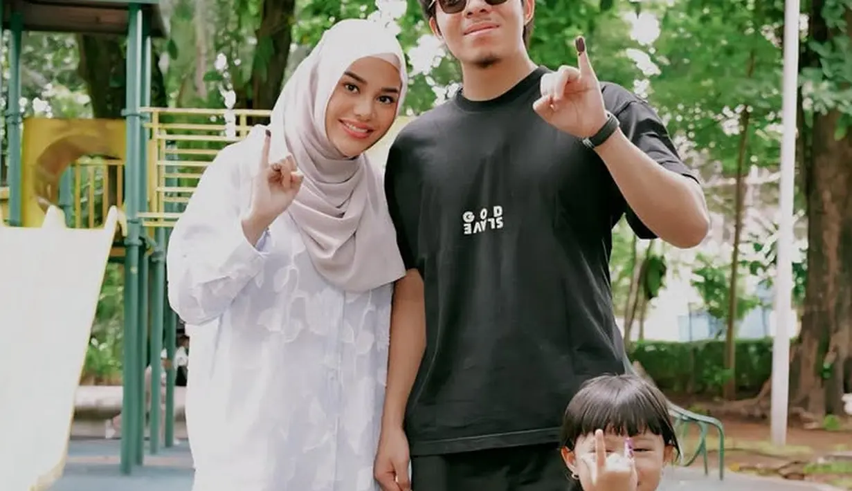 Aurel Hermansyah hadir nyoblos bersama suami dan anaknya. Ia memilih tampil dengan kemeja lengan panjang putih bertekstur dipadukan celana panjang warna senada dan kerudung coklat muda. [@aurelie.hermansyah]