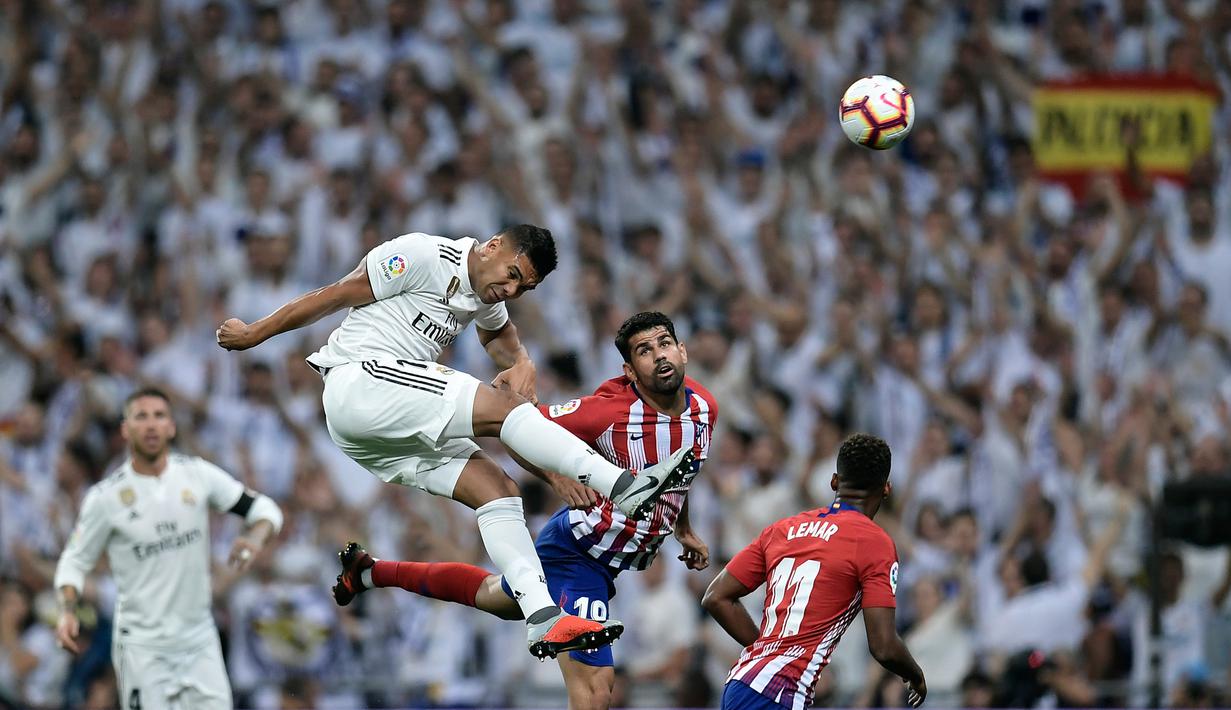 Gelandang Real Madrid, Casemiro, duel udara dengan striker Atletico Madrid, Diego Costa, pada laga La liga di Stadion Santiago Bernabeu, Madrid, Sabtu (29/9/2018). Kedua klub bermain imbang 0-0. (AFP/Oscar Del Pozo)
