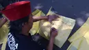 Salah satu warga membantu menuliskan nama Nina Carolina atau yang akrab dikenal dengan panggilan Mpok Alpa sesaat sebelum jenazah tiba di rumah duka, kawasan Ciganjur, Jakarta pada Jumat Jumat (15/8/2025). (KapanLagi.com/Budy Santoso)