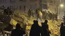 Orang-orang berkumpul di sekitar bangunan yang runtuh di Pazarcik, di provinsi Kahramanmaras, Turki selatan, Senin dini hari, 6 Februari 2023. Gempa berkekuatan magnitudo 7,8 telah menyebabkan kerusakan signifikan di tenggara Turki dan Suriah dan dikhawatirkan banyak korban jiwa. (Depo Photos via AP)
