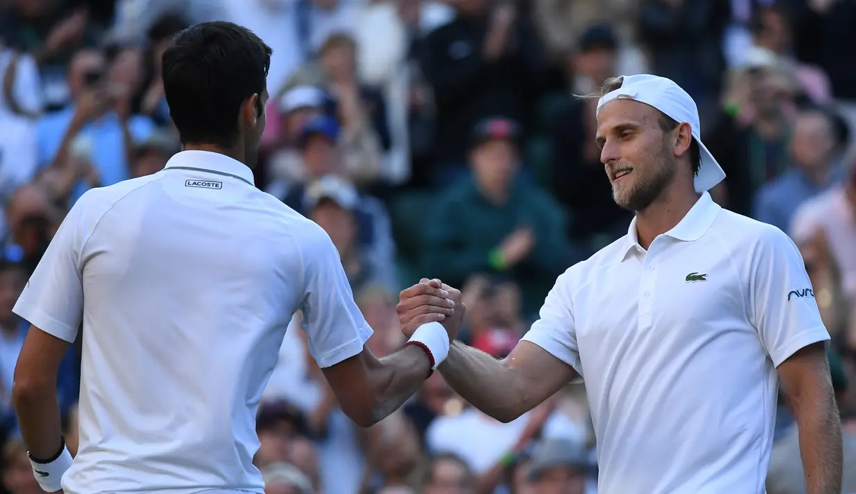 Petenis Serbia, Novak Djokovic berjabat tangan dengan petenis AS Denis Kudla setelah memenangi babak kedua Wimbledon di All England Lawn Tennis Club, London, Kamis (4/7/2019) dini hari. Djokovic melangkah ke babak ketiga setelah menang dengan skor 6-3 6-2 6-2. (Ben STANSALL/AFP)