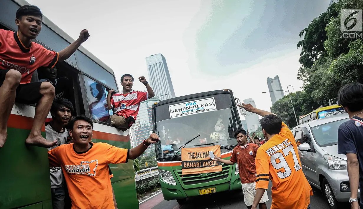 Suporter Persija bersorak saat menuju stadion Gelora Bung Karno, Jakarta, Minggu (9/12). Antusiasme ribuan suporter Persija bersiap mendukung tim kesayangannya bertanding melawan Mitra Kukar. (Liputan6.com/Faizal Fanani)