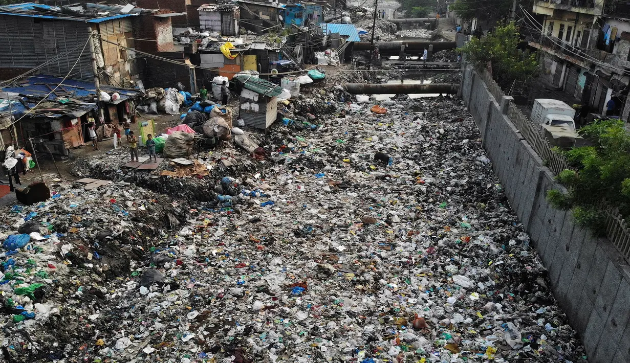 Pandangan udara menunjukkan anak-anak berdiri di dekat saluran pembuangan air yang dipenuhi sampah di lingkungan berpenghasilan rendah di New Delhi, India (4/10/2019). (AFP Photo/Noemi Cassanelli)