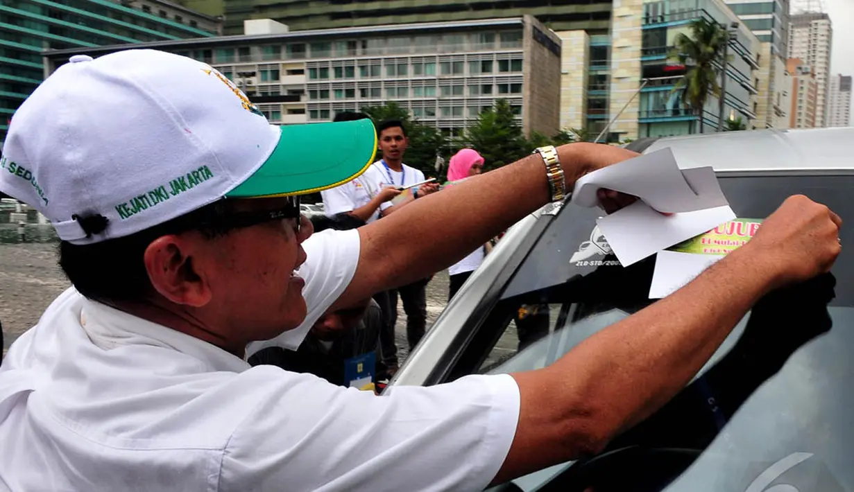 Seorang aktivis memasang striker anti-korupsi ke salah satu mobil yang melintas di Bundaran HI, Jakarta, Selasa (12/9/2014). (Liputan6.com/Johan Tallo)
