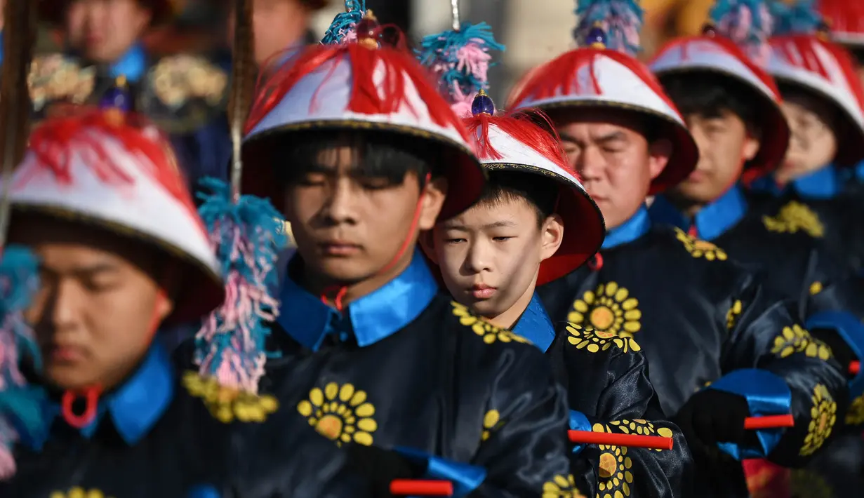 Para pemain yang berpakaian seperti penjaga kekaisaran mengambil bagian dalam pertunjukan ulang upacara pengorbanan di pameran kuil taman Ditan pada hari kedua Tahun Baru Imlek Naga di Beijing pada 11 Februari 2024. (GREG BAKER/AFP)