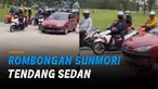 Seorang mengetuk jendela, sementara seorang lainnya menendang bagian depan mobil.