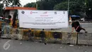 Warga melompati beton pembatas penutupan sementara perlintasan KRL Commuter Line sebidang di Pasar Minggu, Jakarta, Selasa (9/5). Penutupan secara permanen akan dilakukan pada 2 Juni mendatang. (Liputan6.com/Helmi Fithriansyah)