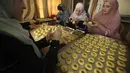 <p>Perempuan Palestina membuat kue tradisional berisi kurma dan kacang-kacangan dalam persiapan untuk liburan Idul Fitri, di kota Hebron, Tepi Barat, pada 28 April 2022. Seluruh umat Muslim di dunia akan menandai berakhirnya bulan suci Ramadhan dengan Idul Fitri. (HAZEM BADER / AFP)</p>