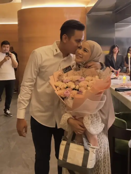 <p>Ia pun membawa tas putih dengan strap hijau. Sementara sang suami mengenakan kemeja putih lengan panjang dipadukan celana hitam. [@chafrederica]</p>