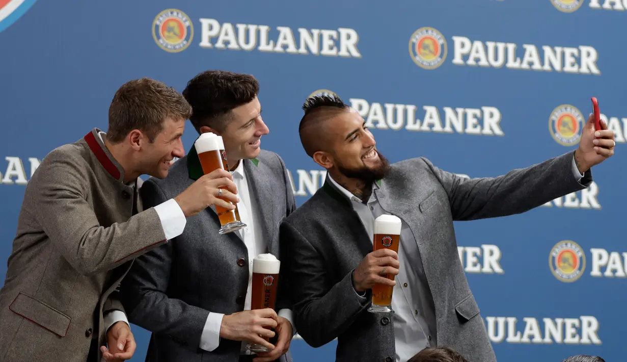 Pemain Bayern Thomas Mueller, Robert Lewandowski dan Arturo Vidal berselfie saat melakukan pemotretan sebuah perusahaan bir di Munich, Jerman, (13/9). (AP Photo / Matthias Schrader)