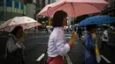 Pejalan kaki berjalan dengan payung di tengah hujan saat Topan Lan menuju pulau utama Jepang Honshu di distrik Ginza Tokyo pada 13 Agustus 2023. (AP Photo/Philip Fong)