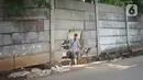 Pejalan kaki melewati tembok berlubang di Terminal Kampung Rambutan, Jakarta, Kamis (19/12/2019). Jauhnya akses bagi pejalan kaki menjadikan tembok berlubang tersebut pintu alternatif untuk keluar dan masuk Terminal Kampung Rambutan. (Liputan6.com/Immanuel Antonius)
