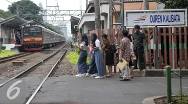 Penyeberang jalan menunggu kereta commuterline melintas di perlintasan sebidang Duren Kalibata, Jakarta, Selasa (13/9). Dirjen Kemenhub usulkan Pemprov DKI Jakarta untuk menutup 19 perlintasan sebidang di wilayah DKI Jakarta. (Liputan6.com/Yoppy Renato)