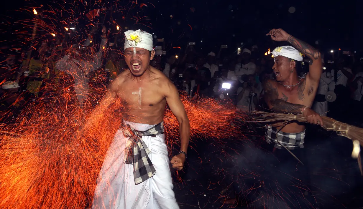 Seorang pria Bali dipukul dengan daun kelapa yang menyala saat ritual Lukat Gni di Klungkung, Bali (16/3). Tradisi lukat gni ini berasal dari dua kata yakni ‘lukat’ dan ‘gni’, malukat atau pembersihan, gni artinya api. (AP Photo / Firdia Lisnawati)
