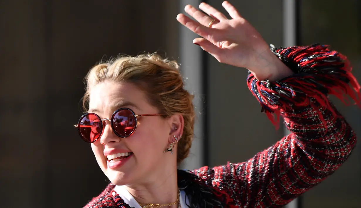 Aktris AS Amber Heard menyapa penggemarnya saat tiba untuk menghadiri malam pembukaan Festival Film Cannes ke-72 di Hotel Martinez, Prancis (13/5/2019). Aktris 33 tahun ini mengenakan kaca mata merah, perhiasan emas, dan membawa tas rantai-tali YSL. (AFP Photo/Alberto Pizzoli)