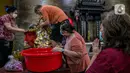 Seorang jemaat memperhatikan para jemaat lain yang sedang membersihkan patung di Vihara Amurva Bhumi, Jakarta, Kamis (4/2/2021). Ritual mencuci patung dewa serta bersih-bersih ini dilakukan dalam rangka menyambut perayaan Tahun Baru Imlek 2572. (Liputan6.com/Faizal Fanani)