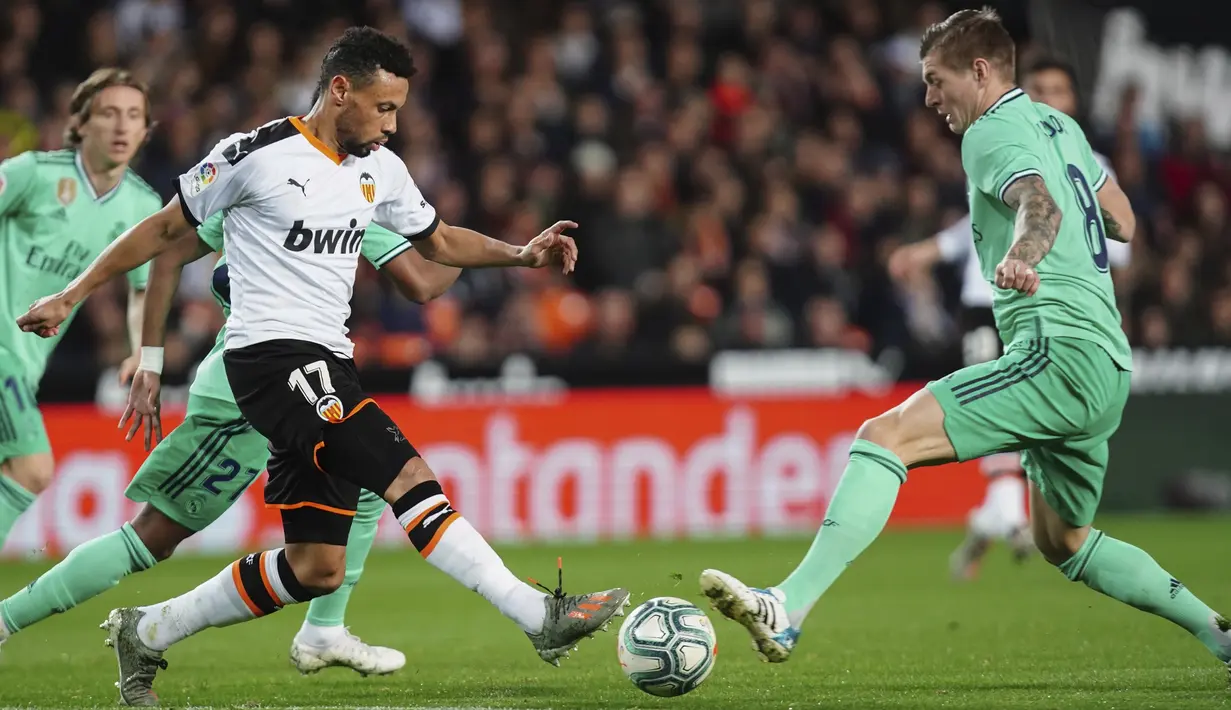 Gelandang Valencia, Francis Coquelin berebut bola dengan gelandang Real Madrid, Toni Kroos pada pertandingan lanjutan La Liga Spanyol di Stadion Mestalla (15/12/2019). Madrid bermain imbang 1-1 atas Valencia. (AP Photo/Alberto Saiz)