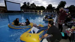 Penonton bersiap-siap untuk menonton pemutaran film buatan sutradara Steven Spielberg "Jaws" dengan ban karet di kolama renang di Brockwell Lido, London, Inggris, Kamis (17/9/2015). (REUTERS/Luke MacGregor)