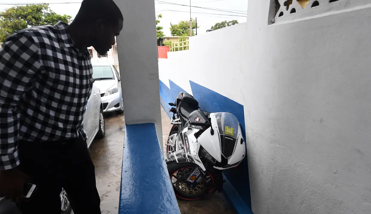 Seorang pria melihat motor yang dikendarai Germaine Mason di kantor polisi Kingston, Jamaika (20/4). Germaine Mason pernah mempersembahkan medali emas pada 2003 untuk Jamaika. (AFP Photo/Jewel Samad)