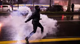 Seorang aktivis antifasis melempar tabung gas air mata ke petugas keamanan setempat saat terjadi huru-hara dalam demonstrasi di Turin, Italia (22/2). (AFP Photo/Piero Cruciatti)