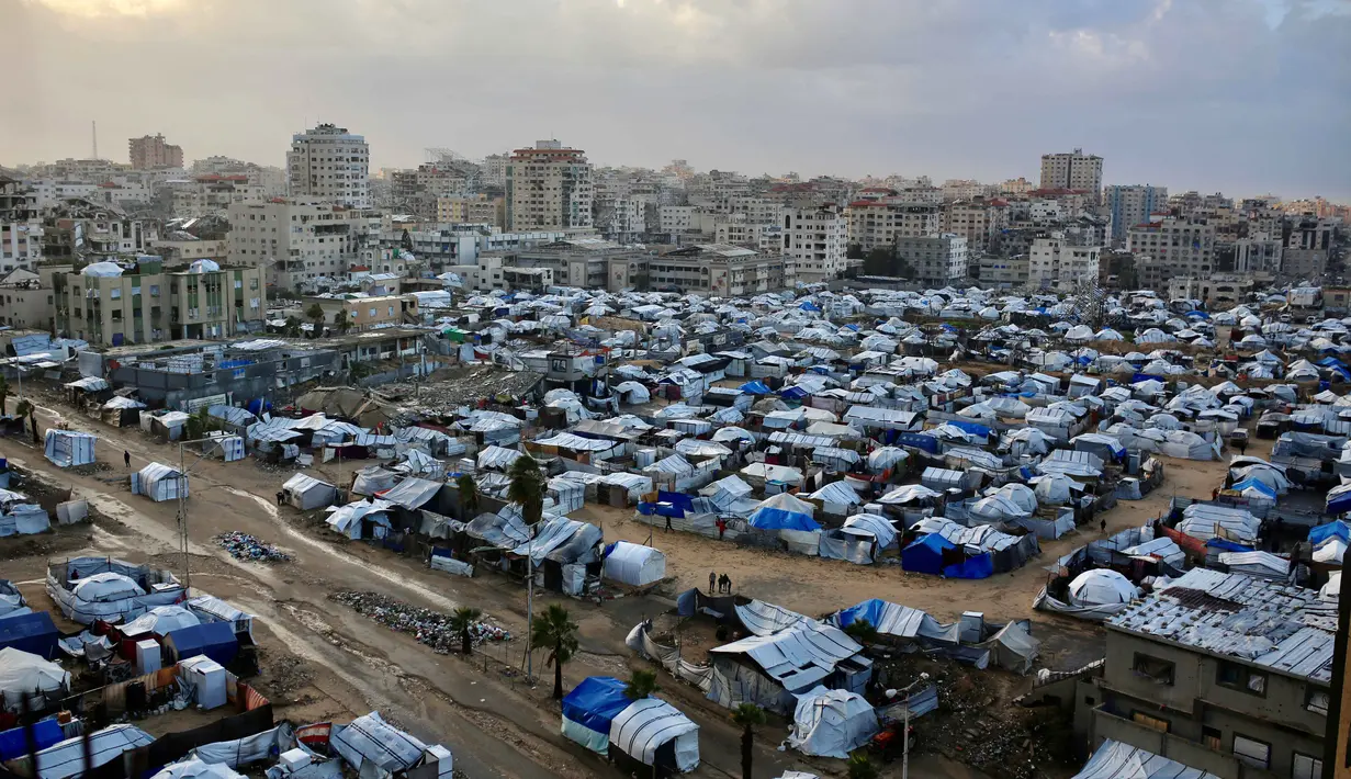 Sementara itu, Kepala Badan Perserikatan Bangsa Bangsa untuk Pengungsi Palestina (UNRWA), Philippe Lazzarini, mengatakan pada Minggu 28 Desember 2025, curah hujan tinggi akan menambah kesengsaraan, keputusasaan, dan angka kematian di Gaza. Tampak dalam foto, tenda-tenda pengungsi Palestina yang melindungi mereka dari kondisi musim dingin yang keras didirikan di lahan terbuka di Kota Gaza, 28 Desember 2025. (Omar AL-QATTAA/AFP)