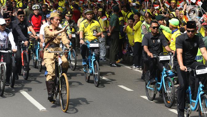 Presiden Joko Widodo atau Jokowi menyapa warga saat mengikuti Bandung Lautan Sepeda, Sabtu (10/11). Jokowi bersepeda mengelilingi Kota Bandung. (Liputan6.com/Angga Yuniar)