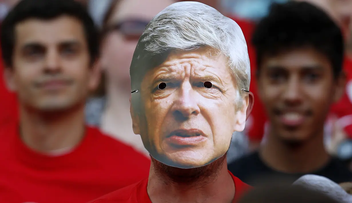 Suporter menggunakan topeng pelatih Arsenal, Arsene Wenger, saat perpisahan di Stadion Emirates (6/5/2018). Selama 22 tahun membesut Arsenal, Wenger telah mempersembahkan 17 gelar dan 704 Kemenangan. (AFP/Ian Kington)