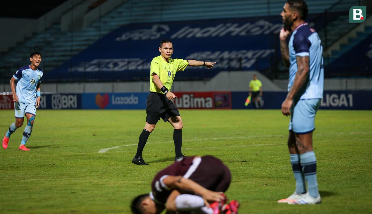 Wasit Steven Yubel Poli menunjuk titik penalti usai pemain PSM Makassar, Muh. Rizky Eka Pratama dilanggar oleh pemain Persela Lamongan dalam laga pekan ke-15 BRI Liga 1 2021/2022 di Stadion Moch. Soebroto, Magelang, Kamis (02/12/2021). (Bola.com/Bagaskara Lazuardi)