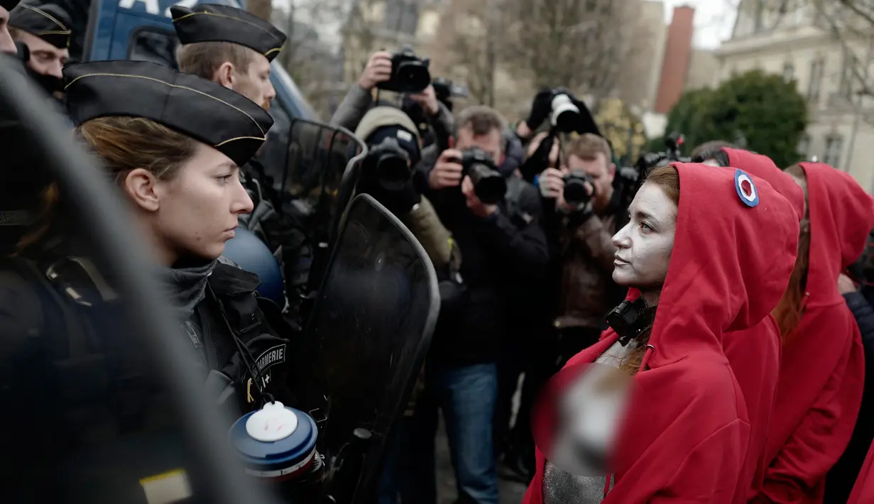 Polisi antihuru-hara menghadang aktivis wanita bertelanjang dada saat aksi protes rompi kuning di Paris, Prancis, Sabtu (15/12). Setelah empat pekan didemo, Presiden Emmanuel Macron kenaikan upah minimum dan konsesi pajak. (AP Photo/Kamil Zihnioglu)