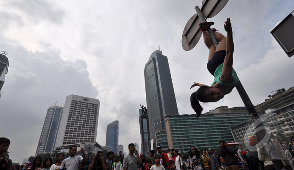  Salah satu aksi yang diperagakan pegiat 'Pole Dance'  di Bundaran HI, Jakarta, Minggu (18/1/2015). (Liputan6.com/Miftahul Hayat)