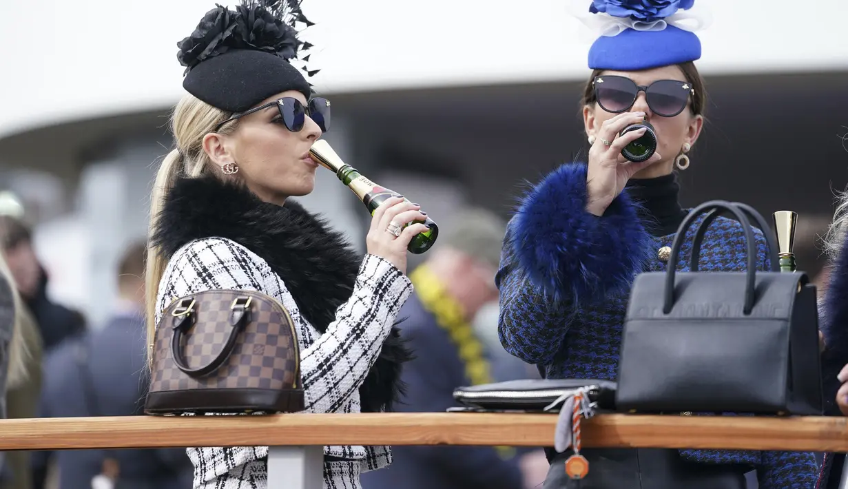 Dua wanita menikmati sampanye pada hari pertama Festival Cheltenham di Cheltenham Racecourse, Inggris, Selasa (15/3/2022). Kehadiran para wanita memberikan nuansa tersendiri di kompetisi pacuan kuda tersebut. (Mike Egerton/PA via AP)