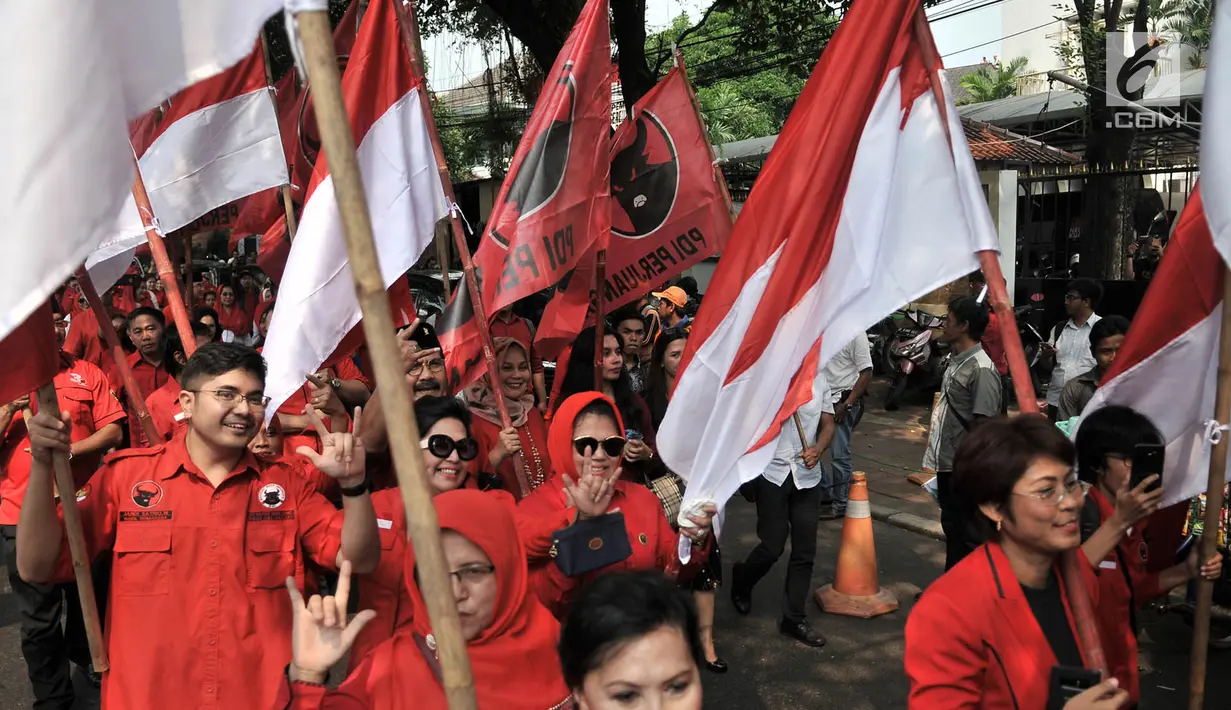 Kader PDIP membawa bendera saat menuju Kantor KPU, Jakarta, Selasa (17/7). Kedatangan anggota PDIP untuk mendaftarkan bakal caleg di KPU diiringi pawai bendera, ondel-ondel, musik hingga wanita cantik. (Merdeka.com/Iqbal S. Nugroho)