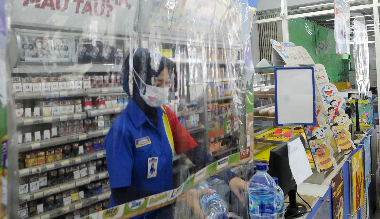 Pekerja melayani pembeli dari balik plastik pembatas pada sebuah minimarket di kawasan Cinere, Depok, Jawa Barat, Rabu (8/4/2020). Penggunaan plastik pembatas tersebut bertujuan untuk mengantisipasi penyebaran virus corona atau COVID-19 sebagai bentuk social distancing. (merdeka.com/Arie Basuki)